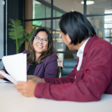 Woman in Purple Blazer Smiling while Holding a Pen