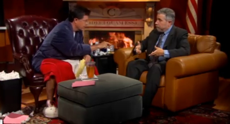 Stephen Colbert wearing the NASE's bunny slippers while interviewing Paul Krugman.
